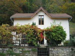 a small white house behind a stone fence at la quatorze in Baume-les-Dames