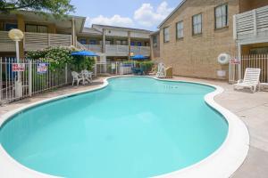 una grande piscina blu di fronte a un edificio di Motel 6-Baytown, TX - Baytown East a Baytown