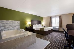 a hotel room with a bed and a bath tub at Quality Inn & Suites Big Rapids near University in Big Rapids +27 photos