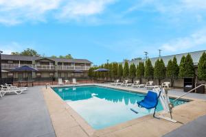 einen Pool in einem Resort mit einem blauen Stuhl und Tischen in der Unterkunft Quality Inn & Suites in Big Rapids