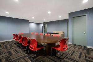 a conference room with a wooden table and red chairs at Quality Inn & Suites in Big Rapids