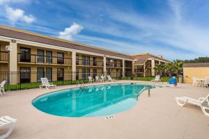 einen Pool in einem Resort mit Stühlen und einem Gebäude in der Unterkunft Quality Inn Coliseum in Charleston