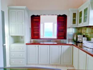 Una cocina con gabinetes blancos y una ventana. en Beautiful Seaside 2BR Apartments, en Christ Church