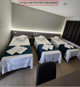 a room with three beds with towels on them at HOTEL CAMPO GRANDE in Campo Grande