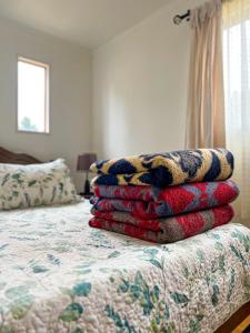 a stack of blankets sitting on top of a bed at Casa En El Tabo Magnolia in El Tabo