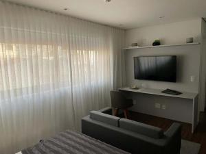 Zimmer mit einem Sofa, einem TV und einem Stuhl in der Unterkunft Studio Aconchegante in São Paulo