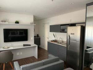 eine Küche mit einem Kühlschrank aus Edelstahl und einem Sofa in der Unterkunft Studio Aconchegante in São Paulo