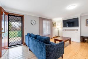 a living room with a blue couch and a table at Welcoming Ambiant 3BR Abode in Tanunda