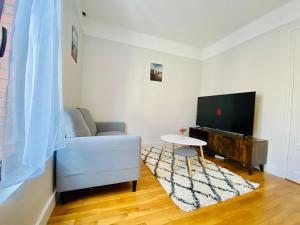 a living room with a white couch and a tv at Cozy Appart'3 - Centre ville & Proche Gare - Cozy Houses in Massy