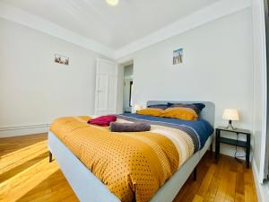 Un dormitorio con una cama grande con mantas y almohadas de colores. en Cozy Appart'3 - Centre ville & Proche Gare - Cozy Houses, en Massy