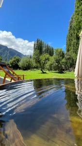 a pool of water with a table and trees at Huella Patagonia Lodge in Puerto Dunn