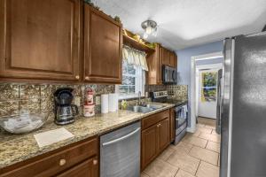 a kitchen with wooden cabinets and a stainless steel refrigerator at Dazzling Centrally Located Ocean View w Huge Private Yard, 2 Decks, Firepit, BBQ in Myrtle Beach
