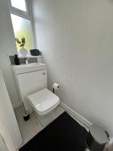 a white bathroom with a toilet and a window at 2 bedroom with garden- Wembley in Preston