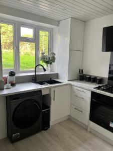 a kitchen with white cabinets and a black dishwasher at 2 bedroom with garden- Wembley in Preston