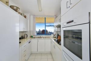 Una cocina blanca con gabinetes blancos y una ventana. en Freddie's at St Tropez, en The Entrance
