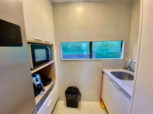 a small kitchen with a sink and a microwave at Flat 113 Eco Resort Praia dos Carneiros in Praia dos Carneiros