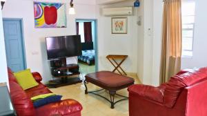 sala de estar con muebles de cuero rojo y TV en The Limes Apartments, en Grand Anse