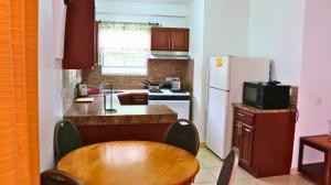 eine kleine Küche mit einem Tisch und einem Kühlschrank in der Unterkunft The Limes Apartments in Grand Anse