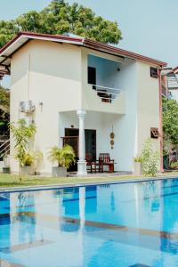 Villa con piscina frente a una casa en Riverside Cabanas, en Mirissa