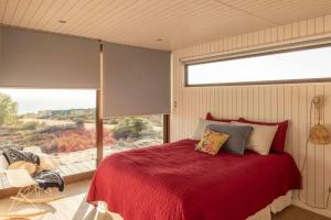 1 dormitorio con cama roja y ventana grande en Preciosa casa para disfrutar en familia CASA REWE, en Los Vilos