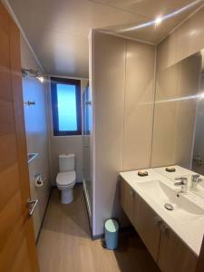a bathroom with a toilet and a sink and a mirror at Preciosa casa para disfrutar en familia CASA REWE in Los Vilos