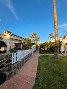 a sidewalk in front of a house with a palm tree at Bungalow con jardín y piscina in San Bartolomé de Tirajana