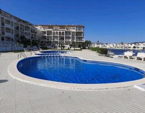 una gran piscina azul frente a un gran edificio en 2 habitacions, aire fred i calent, piscina, parking, en Empuriabrava