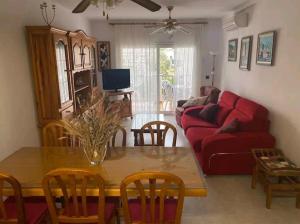 a living room with a table and a red couch at 2 habitacions, aire fred i calent, piscina, parking in Empuriabrava