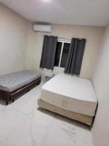 two twin beds in a room with a window at Novo Lar Itapema-2 in Itapema