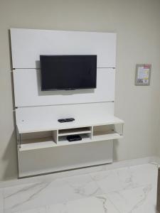 a white entertainment center with a tv on a wall at Novo Lar Itapema-2 in Itapema