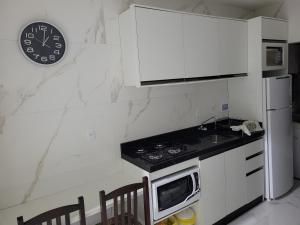 a kitchen with a stove and a clock on the wall at Novo Lar Itapema-2 in Itapema