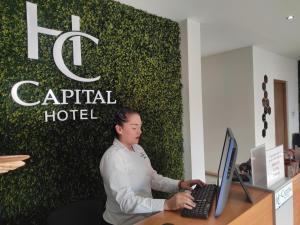 Capital Hotel في مونكلوفا: امرأة تجلس في مكتب مع جهاز كمبيوتر محمول