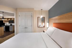 a bedroom with a large white bed and a kitchen at Candlewood Suites-Augusta, an IHG Hotel in Augusta