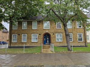 uma casa de tijolos com uma porta azul e uma árvore em Cosy in Catford two bed near station em Beckenham