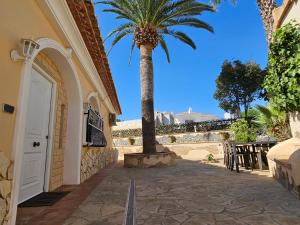 a palm tree next to a building with a door at Villa Las Adelfas (escapada ideal en Costa Blanca) in Calpe