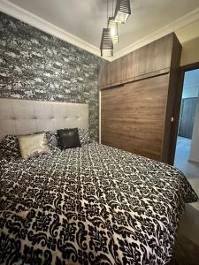 Schlafzimmer mit einem Bett mit einer schwarzen und weißen Bettdecke in der Unterkunft Appartement karima in Marrakesch