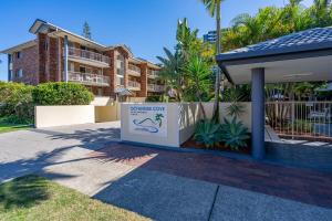 a sign in front of a building with palm trees at Oceanside Cove in Gold Coast