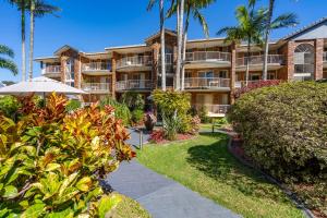un edificio de apartamentos con palmeras y una pasarela en Oceanside Cove, en Gold Coast