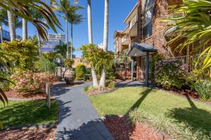 a walkway in front of a house with palm trees at Oceanside Cove in Gold Coast