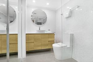 a bathroom with a toilet and a sink and a mirror at Oceanside Cove in Gold Coast