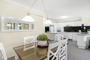 cocina y comedor con mesa de cristal y sillas blancas en Oceanside Cove, en Gold Coast