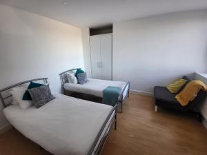 a room with two beds and a couch and a chair at Vetrelax Basildon City Center Apartment in Basildon