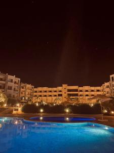 una gran piscina frente a un edificio por la noche en SHARM ENJOY APARTMENTS en Sharm El Sheikh