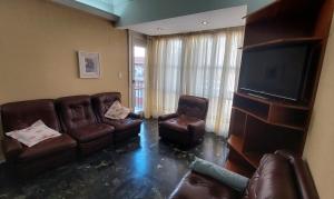 sala de estar con muebles de cuero y TV de pantalla plana en Muy Amplio Departamento en el Centro a cuadras del Mar y Casino en Mar del Plata