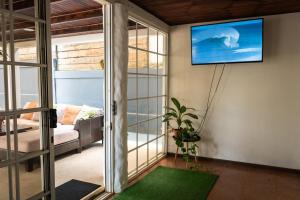 uma sala de estar com televisão na parede em Mai Ke Kai Surf House em Tamarindo