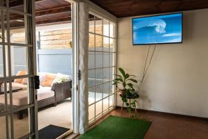 a living room with a tv on the wall at Mai Ke Kai Surf House in Tamarindo