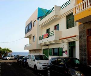 un edificio con coches estacionados frente al océano en Terrazas del Sur, en Los Abrigos