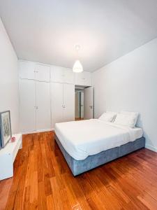 Seaside Elegance and Tranquility: Your Luxurious Porto Getaway في بورتو: غرفة نوم بيضاء مع سرير كبير وأرضيات خشبية