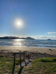 a bench on a beach with the sun in the sky at Tranquil Retreat - Spacious Home for a Relaxing Getaway 