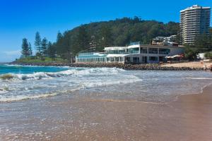 a building on a beach with waves in the sand at Oceanside Cove in Gold Coast